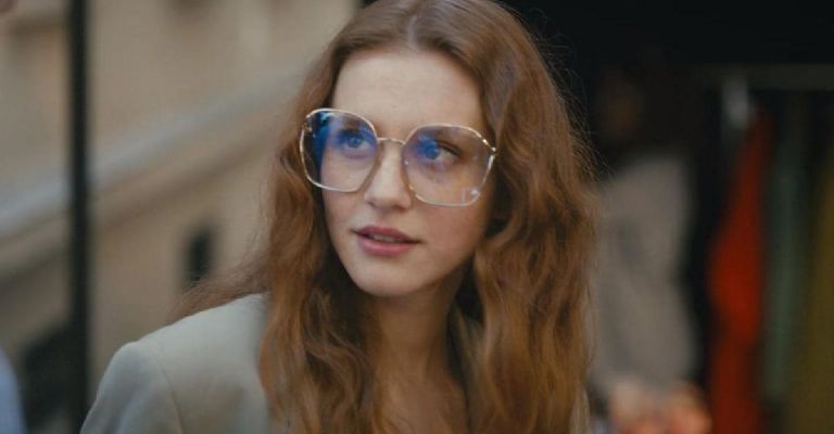 joven mujer pelirroja con grandes lentes mira hacia un costado, escena de la película sé tú misma, de Netflix